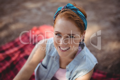 Smiling young woman sitting on mat at olive farm
