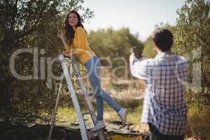 Boyfriend photographing girlfriend on sunny day at olive farm