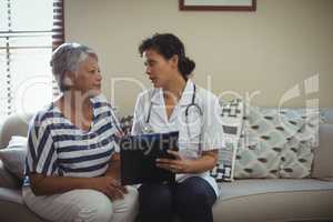 Female doctor interacting with senior woman in living room