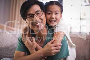 Portrait of smiling father and daughter relaxing on sofa in living room