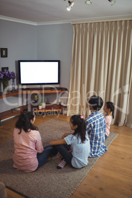 Family watching television together in living room