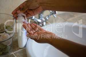 Cropped hands using soap dispenser in bathroom