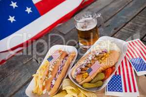 Hot dog and glass of beer with american flag on wooden table