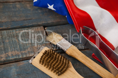 Basting brush and tong with American flag on wooden table