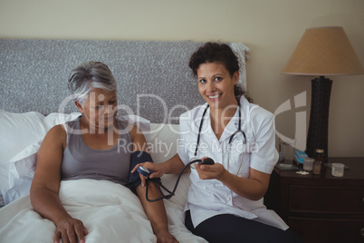 Female doctor measuring blood pressure of a senior woman