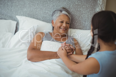 Granddaughter comforting sick grandmother in bed room