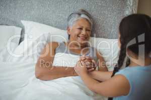 Granddaughter comforting sick grandmother in bed room