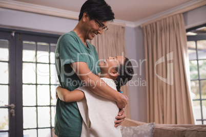 Smiling father and daughter hugging each other in living room