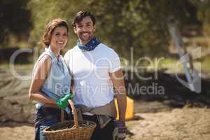 Smiling young couple holding wicker basket at olive farm