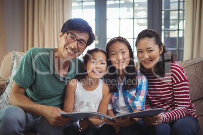 Family with photo album together in living room