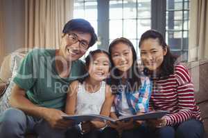 Family with photo album together in living room