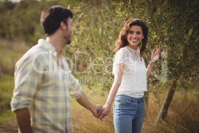 Smiling couple standing by tree at farm