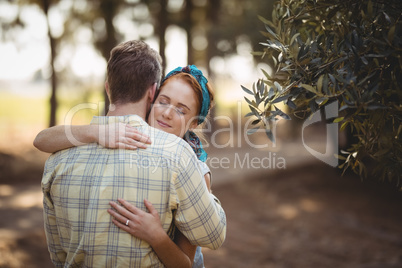 Couple embracing by olive tree at farm