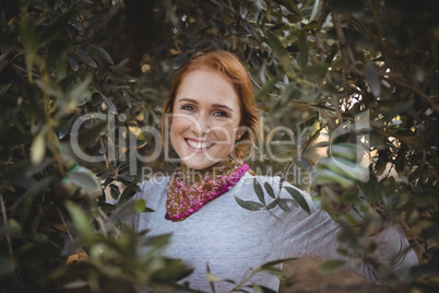 Smiling young woman standing amidst trees at olive farm