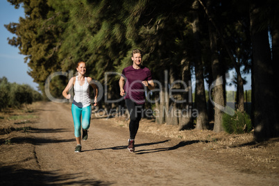 Full length of young couple jogging at farm