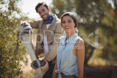 Happy young couple standing by trees at olive farm