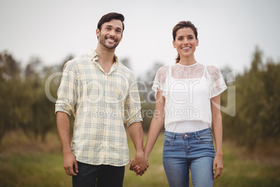 Smiling young couple holding hands at olive farm