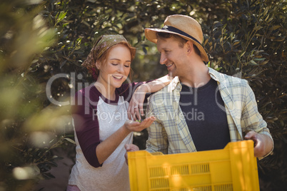 Happy young couple with yellow crate standing at farm