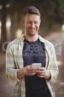 Smiling man using mobile phone at olive farm