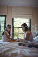 Daughter and mother playing with teddy bear in bed room