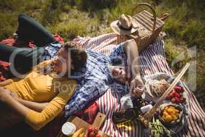 Portrait of happy young man lying with girlfriend on blanket