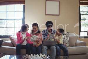 Family using laptop, digital tablet and mobile phone in living room