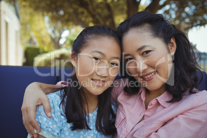 Mother and daughter relaxing on couch outside home