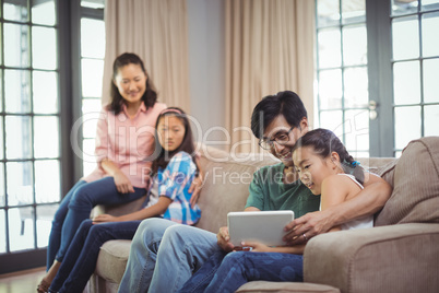 Smiling family using digital tablet together in living room