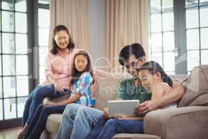Smiling family using digital tablet together in living room