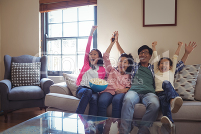 Smiling family watching television together in living room