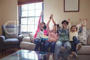 Smiling family watching television together in living room