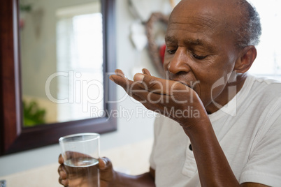 Senior man taking medicine in bathroom