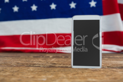American flag and mobile phone arranged on wooden table