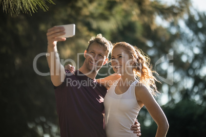 Happy young couple taking selfie on sunny day at farm