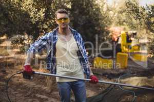 Confident young man using rake at olive farm