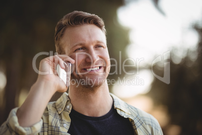 Smiling young man talking on phone at olive farm