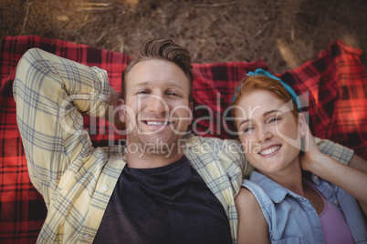 Overhead view of happy young couple resting on mat at farm