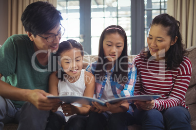 Family watching photo album together in living room