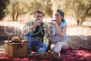 Young couple drinking red wine while sitting at farm