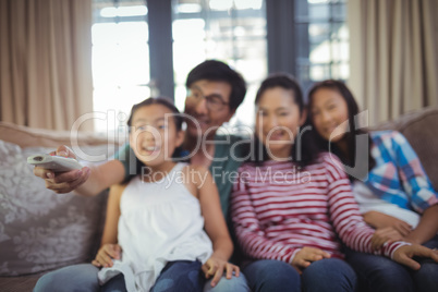 Smiling family watching television together in living room