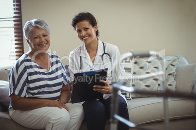 Portrait of female doctor with senior woman in living room