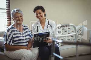 Portrait of female doctor with senior woman in living room