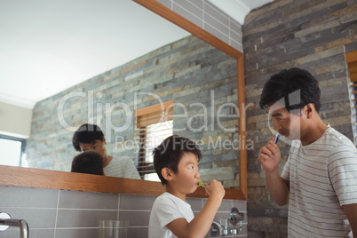 Father and son brushing teeth together in bathroom