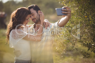 Romantic couple taking selfie by tree