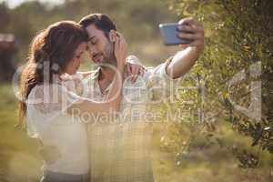 Romantic couple taking selfie by tree