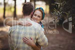Smiling young woman embracing man at olive farm