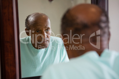 Mirror with reflection of concerned senior man