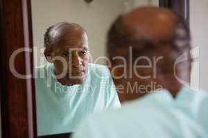 Mirror with reflection of concerned senior man