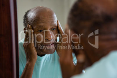 Concerned senior man reflecting on mirror