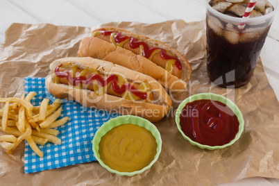 Hot dog, sauces and cold drink on brown paper
